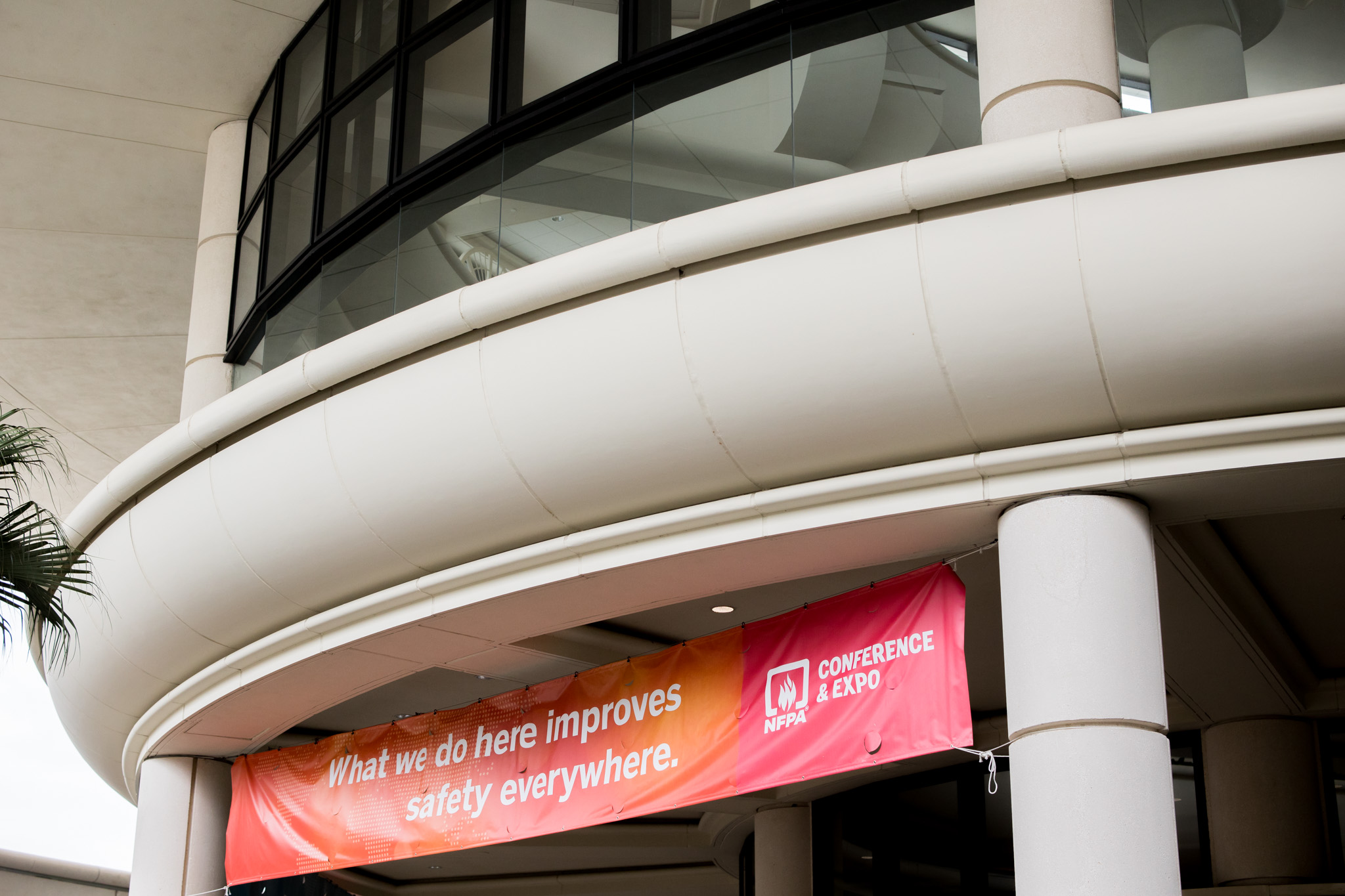 A curved building with tall columns and a balcony. A red and orange banner hangs in front, reading: "What we do here improves safety everywhere." It also displays the NRPA Conference & Expo logo.